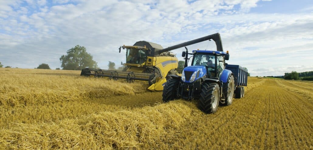 A combine harvester working alongside a tractor on a crop in a field.